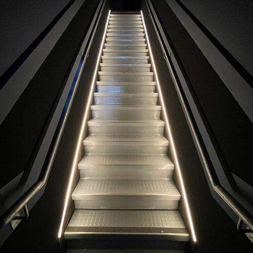 LED neon flex strip lighting installed along indoor staircase handrails
